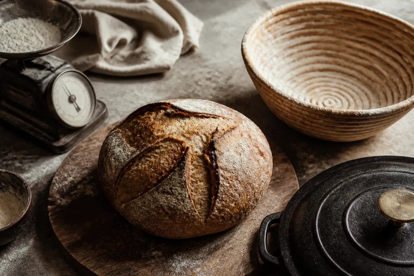Editorial still life of a rustic loaf, a Dutch oven, a scale, and a banneton. Generated graphic, no people.